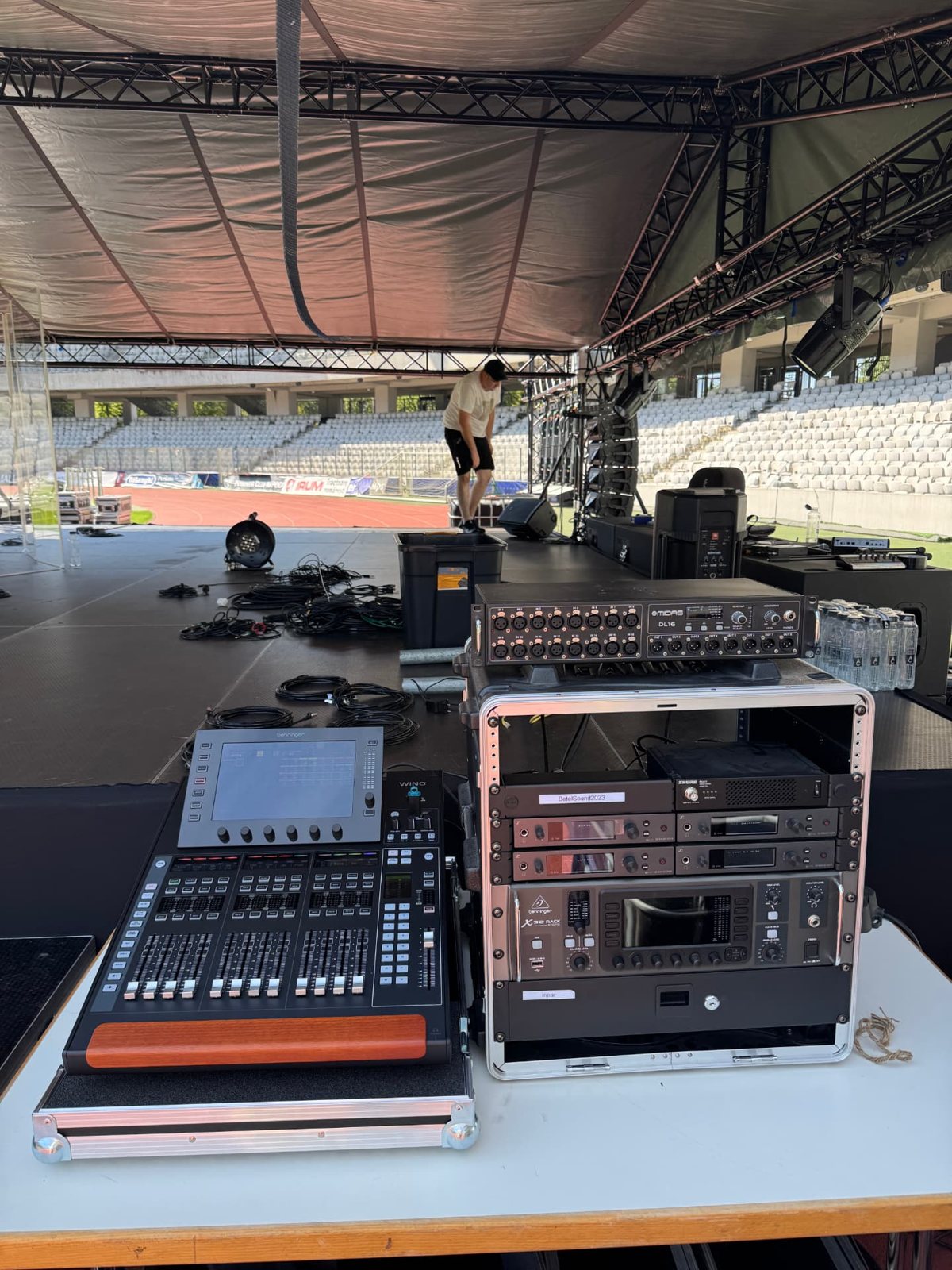 Stage being built in a stadium, with a digital console and racks ready at the side